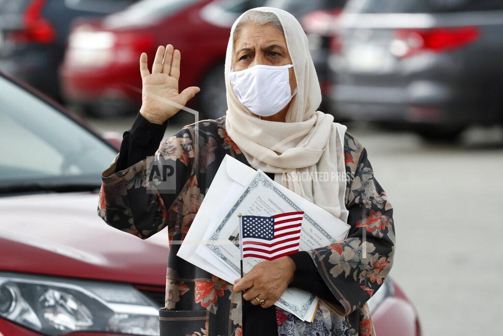 Charlie Neibergall FILE - In this June 26, 2020, file photo, Aisha Kazman Kammawie, of Ankeny, Iowa, takes the oath of allegiance during a drive-thru naturalization ceremony at Principal Park in Des Moines, Iowa. U.S. Citizenship and Immigration Services has transformed under President Donald Trump to emphasize fraud detection, enforcement and vetting, which has delayed processing and contributed to severe fiscal problems. Its revamp came as the administration sought to cut legal immigration by making it more dependent on employment skills and wealth tests. (AP Photo/Charlie Neibergall, File)