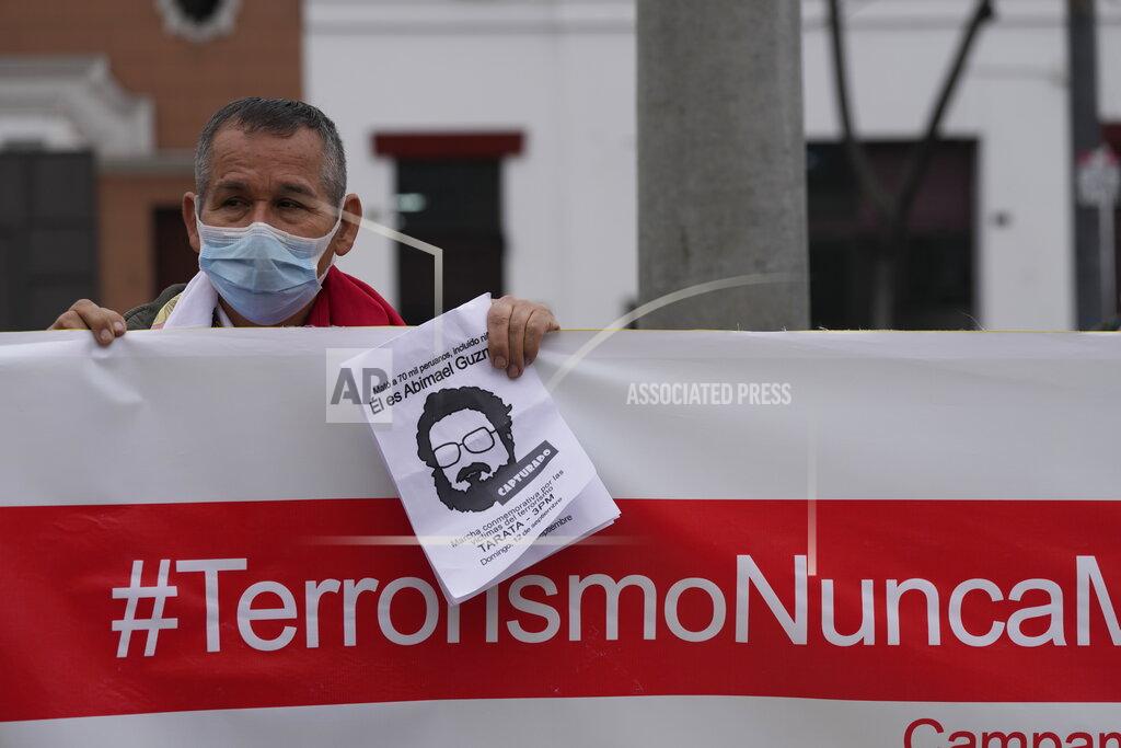 Martin Mejia A man helps hold up a banner with a hashtag that reads in Spanish; "Terrorism never again" as he joins others outside the anti-terrorism directorate to celebrate the death of Abimael Guzman, founder and leader of the Shining Path guerrilla movement, in Lima, Peru, Saturday, Sept. 11, 2021. Guzman who was captured in 1992, died on Saturday in a military hospital after an illness, the Peruvian government said. He was 86. (AP Photo/Martin Mejia)
