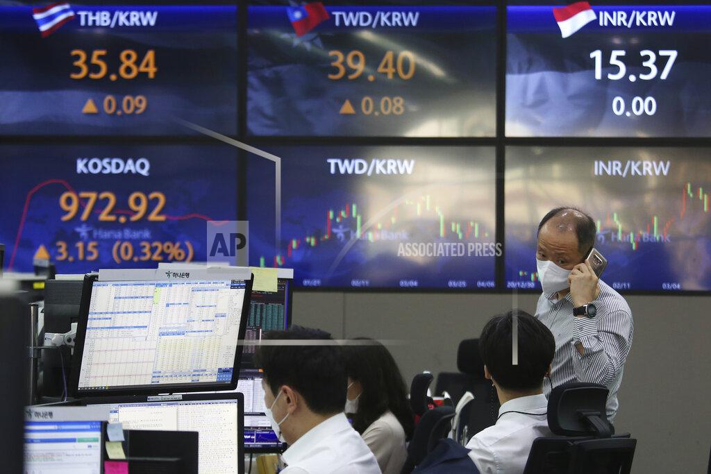 A currency trader wearing a face mask talks with his colleague at the foreign exchange dealing room of the KEB Hana Bank headquarters in Seoul, South Korea, Tuesday, April 6, 2021. Asian shares were mixed Tuesday after a Wall Street rally that reflected some optimism about the economy recovering from the damage of the coronavirus pandemic. (AP Photo/Ahn Young-joon)