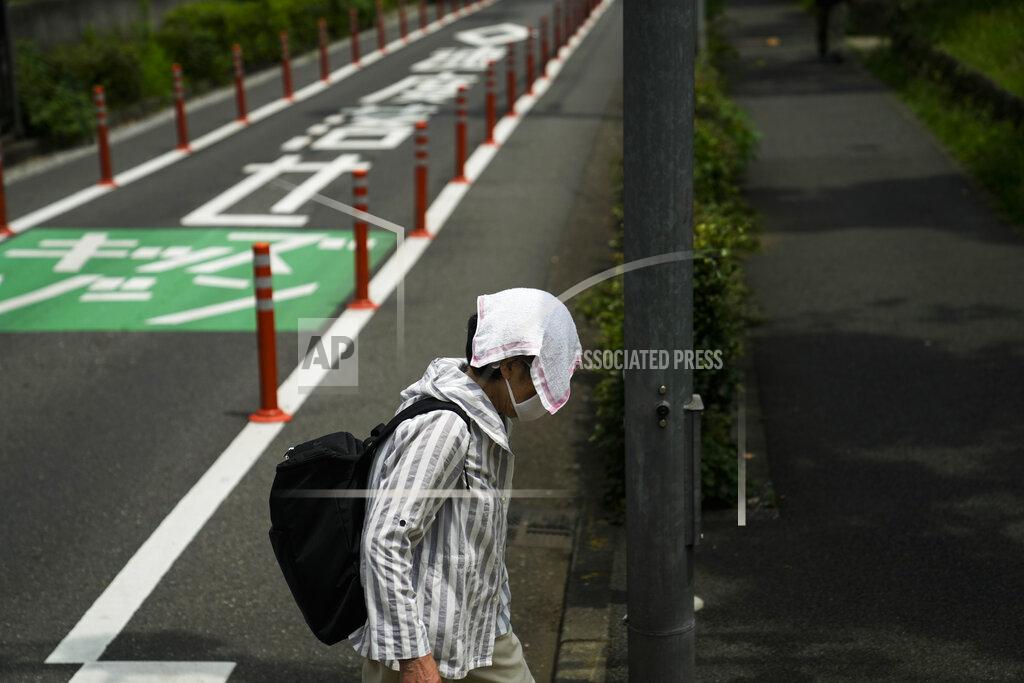 Jae C. Hong An elderly woman walks with a small towel over her head to shield from the sun ahead the 2020 Summer Olympics, Wednesday, July 14, 2021, in Tokyo. (AP Photo/Jae C. Hong)