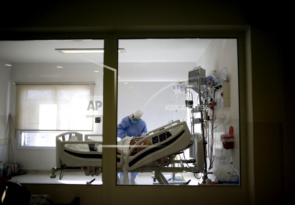 FILE - In this July 14, 2020 file photo, Dr. Adriana Coronel attends a COVID-19 patient at the Eurnekian Ezeiza Hospital on the outskirts of Buenos Aires, Argentina during a government-ordered lockdown to curb the spread of the new coronavirus. People are on edge in Argentina, where the number of new coronavirus cases is surging despite nearly five months of strict limits on movement and activities in Buenos Aires and the surrounding area. (AP Photo/Natacha Pisarenko, File)