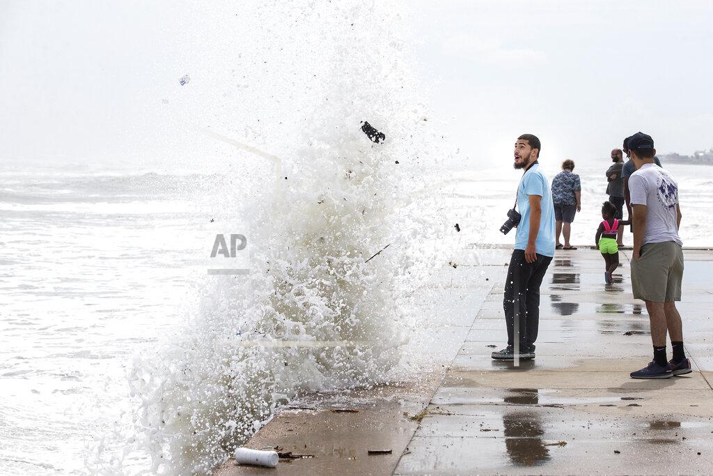 Brett Coomer Jordan Razo steps back as a wave, stirred up by the approach of Hurricane Laura, crashes up and over the seawall Wednesday, Aug. 26, 2020 in Galveston, Texas. (Brett Coomer/Houston Chronicle via AP)