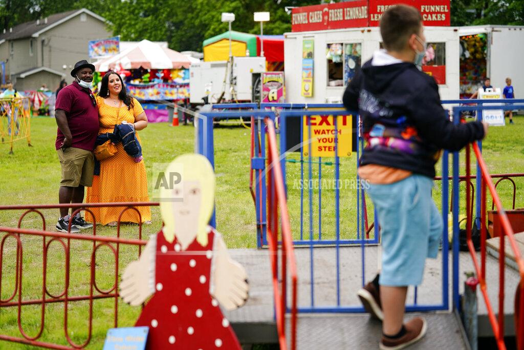 Matt Rourke Alicia Duque, a 35-year-old mother of three and volunteer organizer for the progressive group, Action Together looks on with her husband Steve Edwards as their son Max waits to board a ride at the Edwardsville Pierogi Festival in Edwardsville, Pa., Friday, June 11, 2021. (AP Photo/Matt Rourke)