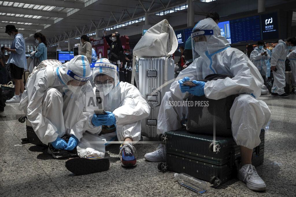 Uncredited Passengers in protective overalls wait for their train at the Hongqiao Railway Station in Shanghai, China Sunday, May 22, 2022. The locked-down Chinese metropolis of Shanghai opens some public transit services as it slowly eases pandemic restrictions that have kept most residents in their housing complexes for more than six weeks. (Chinatopix via AP)