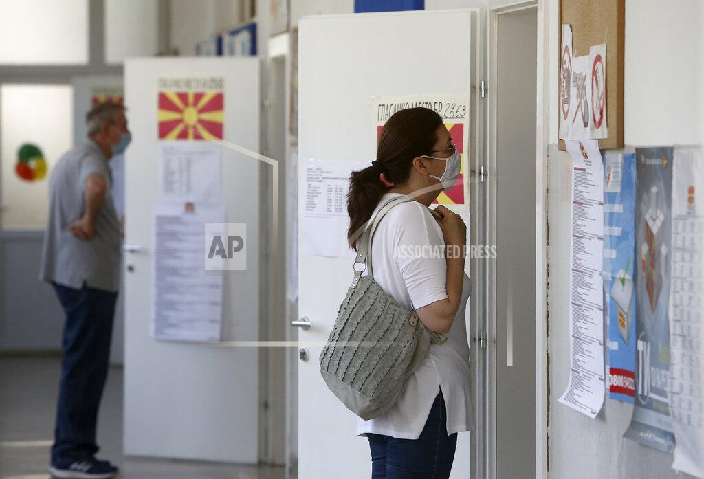Boris Grdanoski People wearing face masks wait before voting for the parliamentary elections in front of polling stations in Skopje, North Macedonia on Wednesday, July 15, 2020. Voters in North Macedonia were heading to polls early on Wednesday in the country's general election despite an alarming spike in coronavirus cases in the tiny Balkan nation. (AP Photo/Boris Grdanoski)