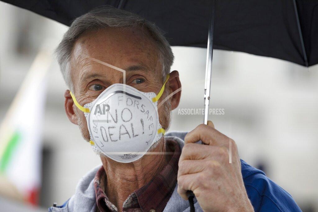 Michael Dwyer New Hampshire State Rep. Mike Sylvia, R-Belmont, wears a protective mask during a demonstration against the government mandated lockdown due to concern about COVID-19 at the State House, Saturday, April 18, 2020, in Concord, N.H. (AP Photo/Michael Dwyer)