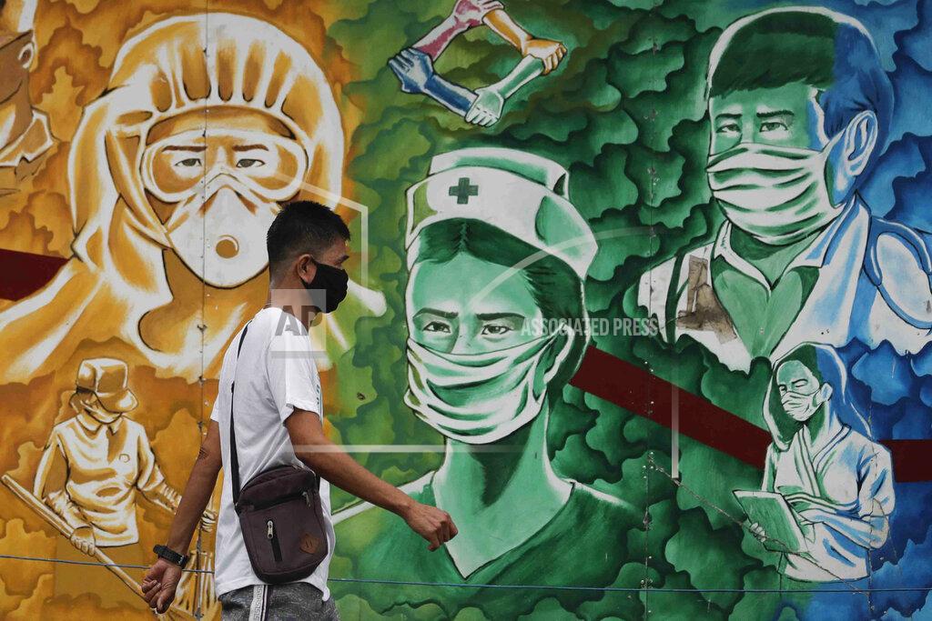 Aaron Favila A man wearing a protective mask to prevent the spread of the coronavirus walks beside a mural of health workers outside the Mission Hospital in Pasig, Philippines, Monday, Feb. 22, 2021. Delays have hounded the delivery of COVID-19 to the Philippines, with officials saying the scheduled arrival on Tuesday of 600,000 doses of donated vaccine from Sinovac Biotech Ltd. may be delayed because the China-based firm still lacks an authorization from Manila's Food and Drug Administration for the emergency use of it's vaccine. (AP Photo/Aaron Favila)