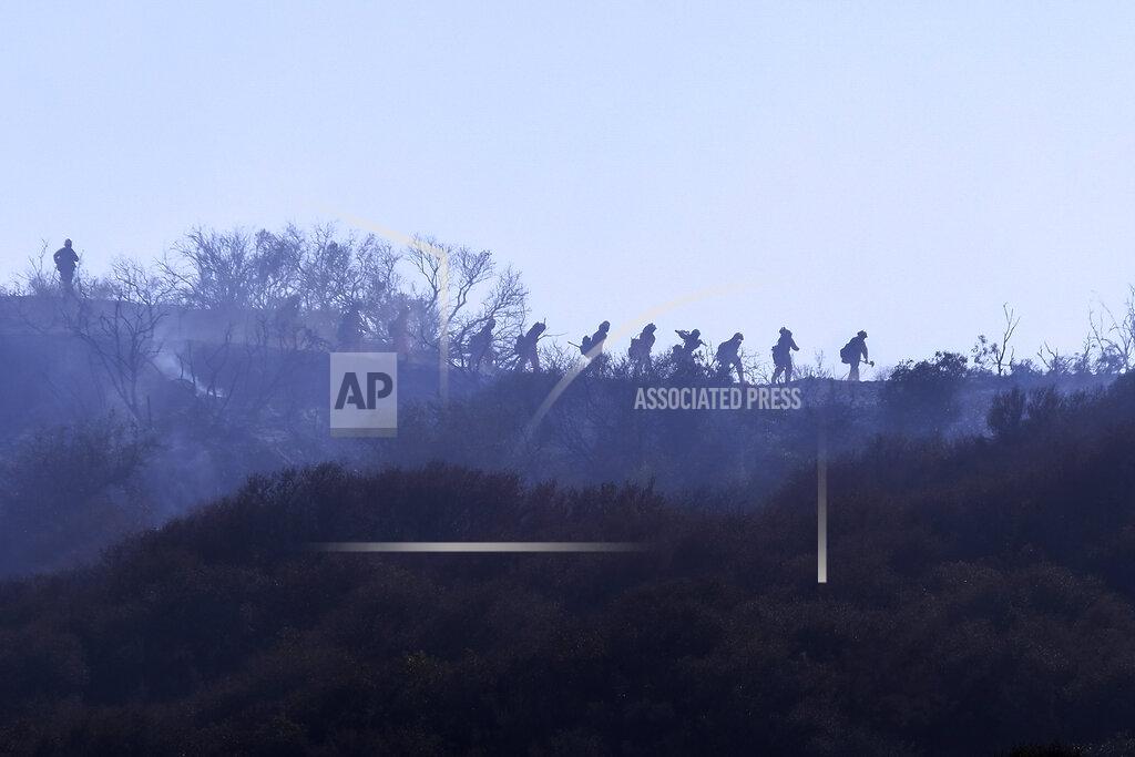 Ringo H.W. Chiu A hotshot hand crew walks in line during a wildfire in Topanga, west of Los Angeles, Monday, July 19, 2021. A brush fire scorched about 15 acres in Topanga today, initially threatening some structures before fire crews got the upper hand on the blaze, but one firefighter suffered an unspecified minor injury. (AP Photo/Ringo H.W. Chiu)