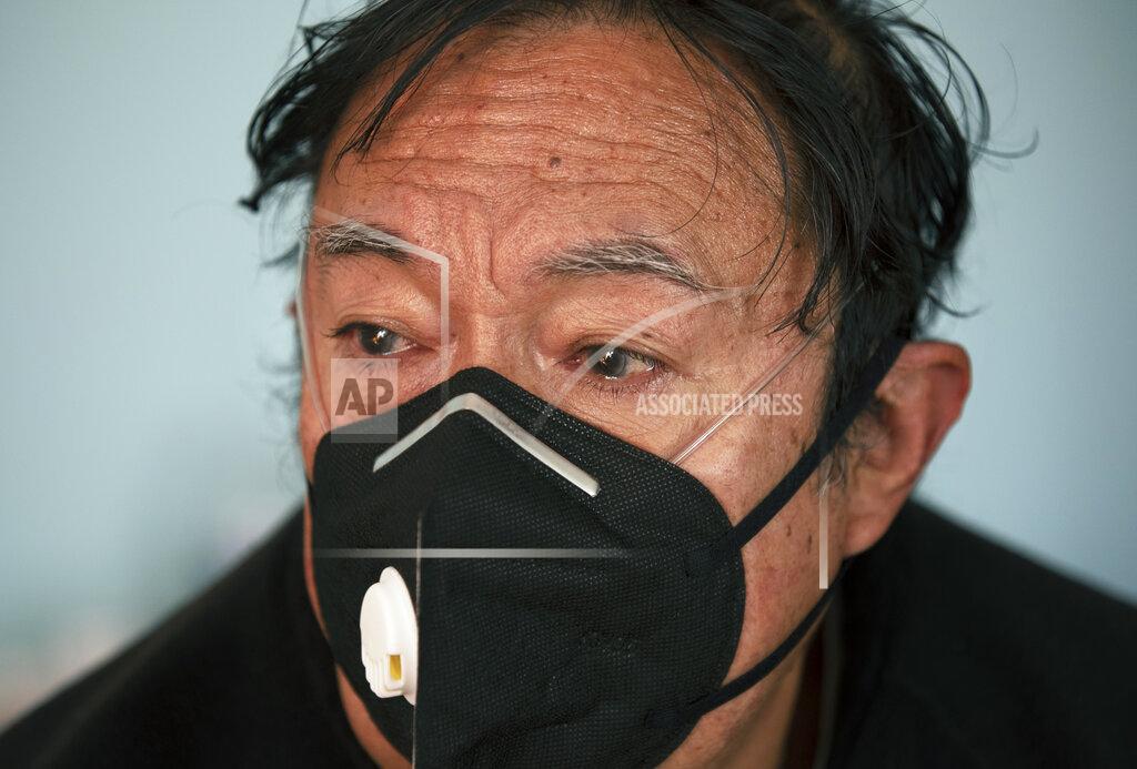 Marco Ugarte Juan Jose Ledesma, 68, gets teary eyed as he talks about his treatment for COVID-19 in his bedroom where he is isolating, as his son sets up a refill of his oxygen tank in Mexico City, Thursday, Dec. 31, 2020. (AP Photo/Marco Ugarte)