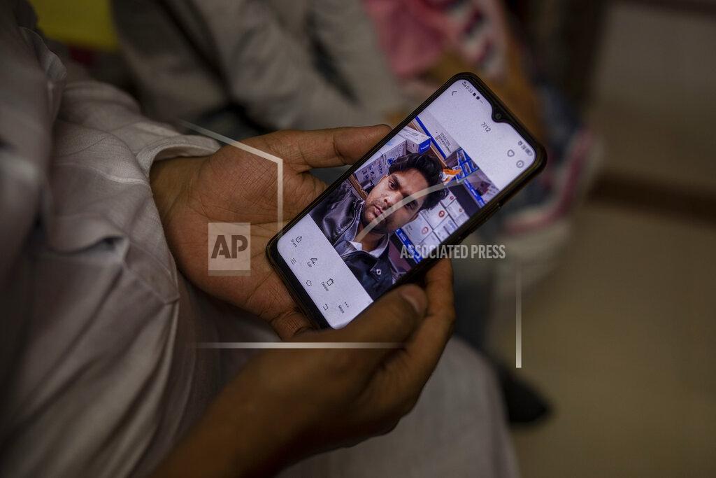 Altaf Qadri Haroon holds a mobile phone with a photograph of his 32 year-old brother who was shot and killed by his Hindu neighbors during the February 2020 communal riots, inside his home in North Ghonda, one of the worst riot affected neighborhood, in New Delhi, India, Friday, Feb. 19, 2021. As the first anniversary of bloody communal riots that convulsed the Indian capital approaches, Muslim victims are still shaken and struggling to make sense of their struggle to seek justice. (AP Photo/Altaf Qadri)
