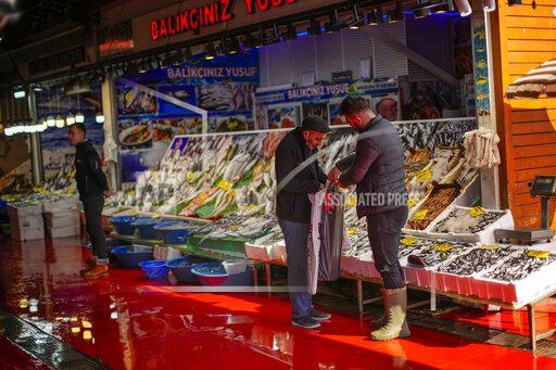 A fishmonger talks to a client at Karakoy fish market in Istanbul, Turkey, Thursday, Oct. 14, 2021. The Turkish lira hit new record lows against the dollar on Thursday after President Recep Tayyip Erdogan sacked senior central bank officials, heightening concerns over the Turkish leader's interference in the bank's activities. (AP Photo/Francisco Seco)