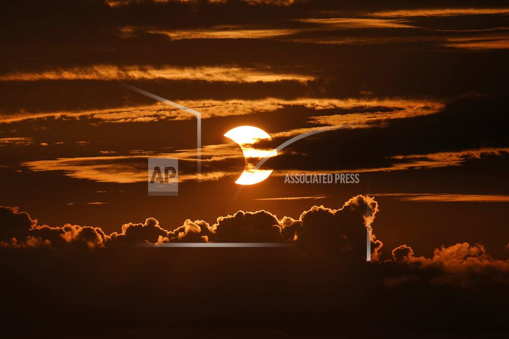 Julio Cortez A partial solar eclipse rises behind clouds, Thursday, June 10, 2021, in Arbutus, Md. (AP Photo/Julio Cortez)