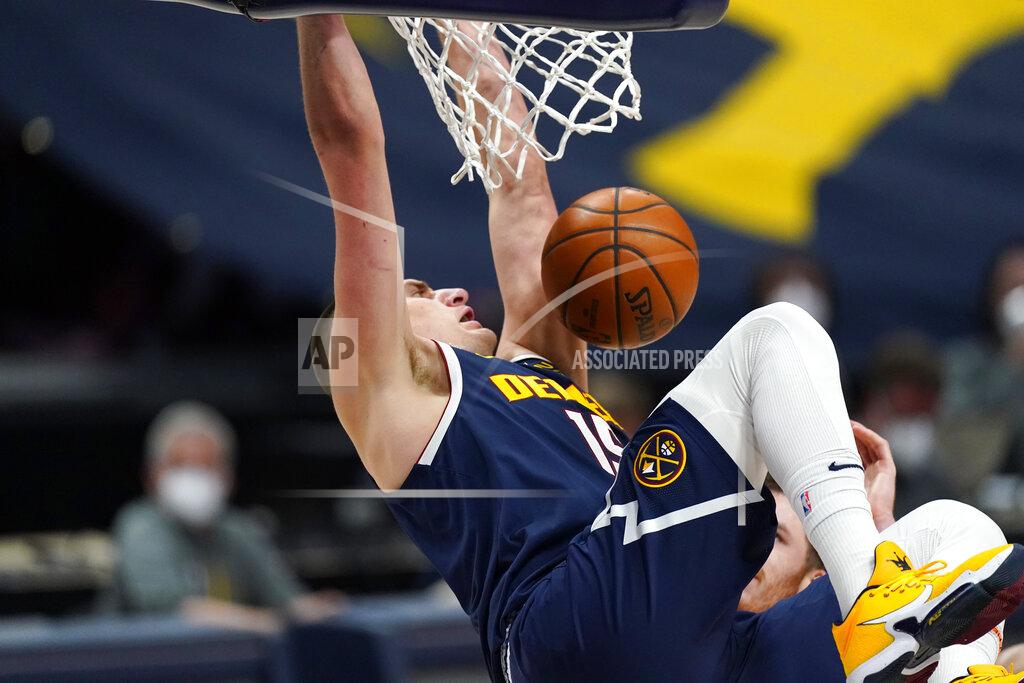 David Zalubowski Denver Nuggets center Nikola Jokic hangs from the rim after dunking against the San Antonio Spurs in the second half of an NBA basketball game Friday, April 9, 2021, in Denver. (AP Photo/David Zalubowski)