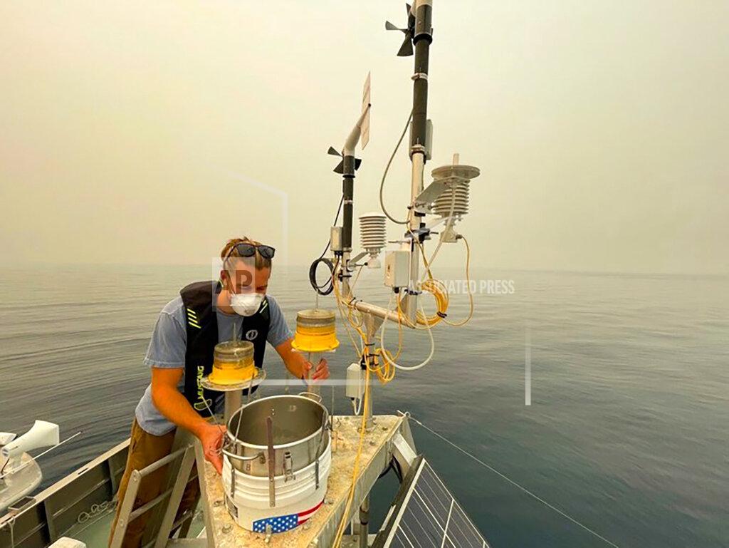 Brant Allen This photo provided by UC Davis shows Brandon Berry, a researcher at the University of California Davis Tahoe Environmental Research Center, examines a collection bucket that scientists are using to measure particles and gauge wildfire's effect on the clarity of Lake Tahoe in Lake Tahoe, Calif., on Aug. 25, 2021. Scientists say it's too soon to draw definite conclusions about the lasting damage that record-setting wildfires will have on Lake Tahoe. But they're not wasting time. Many plan to bring their research plans to the Tahoe Science Advisory Council when it convenes for a scheduled meeting Thursday Sept. 16, 2021. (Brant Allen, UC Davis via AP)