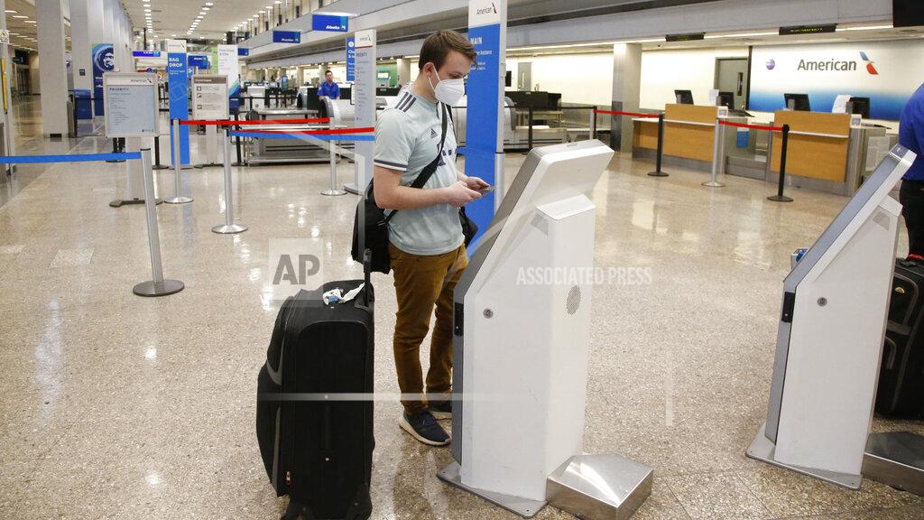 Ethan Cale receives his ticket at the American Airlines ticket counter Thursday, April 30, 2020, in Salt Lake City. American Airlines reports a staggering loss of $2.2 billion for the first quarter, when the new coronavirus began to cause a steep drop in air travel. American Airlines reported Thursday that revenue fell 19% while costs continued to rise even as the virus spread. Air travel within the U.S. has plunged 95% from a year ago, judging by the number of people screened at the nation's airports. (AP Photo/Rick Bowmer)