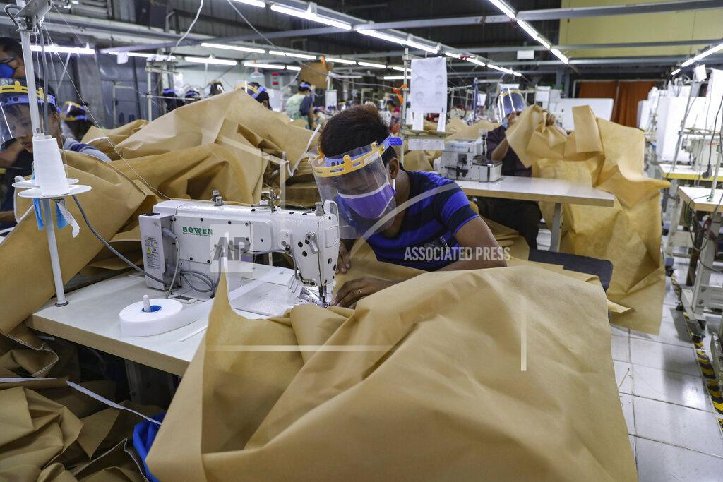 Uncredited FILE - In this May 28, 2020, file photo, a man wearing face mask and face shield to help curb the spread of the new coronavirus, sews surgical gown at a garment factory in Yangon, Myanmar. Garment workers in Myanmar are urging major international brands to denounce the recent military coup there and put more pressure on factories to protect workers from being fired or harassed - or worse arrested and killed for participating in protests. (AP Photo, File)