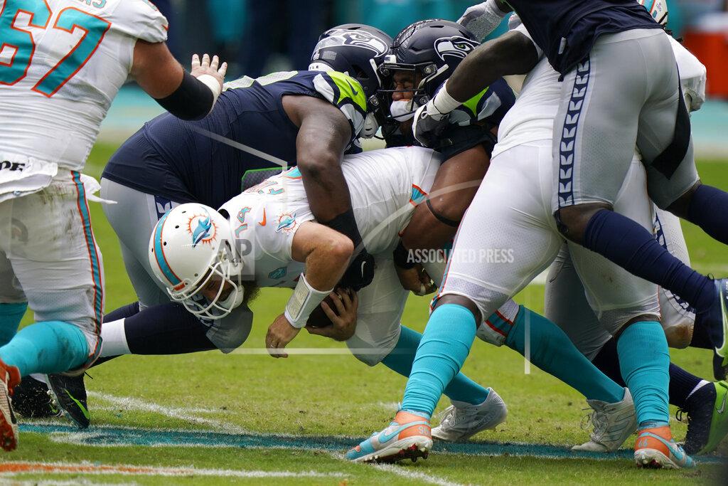 Wilfredo Lee Miami Dolphins quarterback Ryan Fitzpatrick (14) is sacked by Seattle Seahawks defensive tackles Anthony Rush and Bryan Mone, during the first half of an NFL football game, Sunday, Oct. 4, 2020 in Miami Gardens, Fla. (AP Photo/Wilfredo Lee)