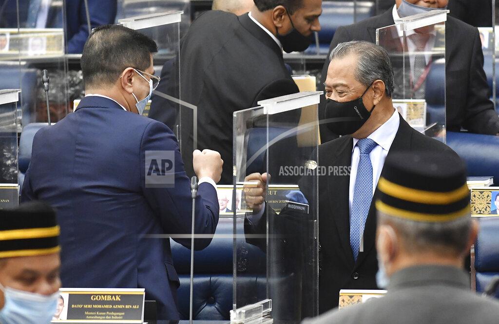 Famer Roheni In this photo release by Malaysia Information Ministry, Malaysia's Prime Minister Muhyiddin Yassin, right, fist-bumps with Minister of International Trade and Industry Azmin Ali after the budget 2021 vote during a session of the lower house of parliament, in Kuala Lumpur, Malaysia Thursday, Nov. 26, 2020. Malaysia's Parliament Thursday approved the government's proposed 2021 budget, throwing a political lifeline to embattled Prime Minister Muhyiddin Yassin amid strong resistance to his nine-month-old leadership. (Famer Roheni/Malaysia's Department of Information via AP)