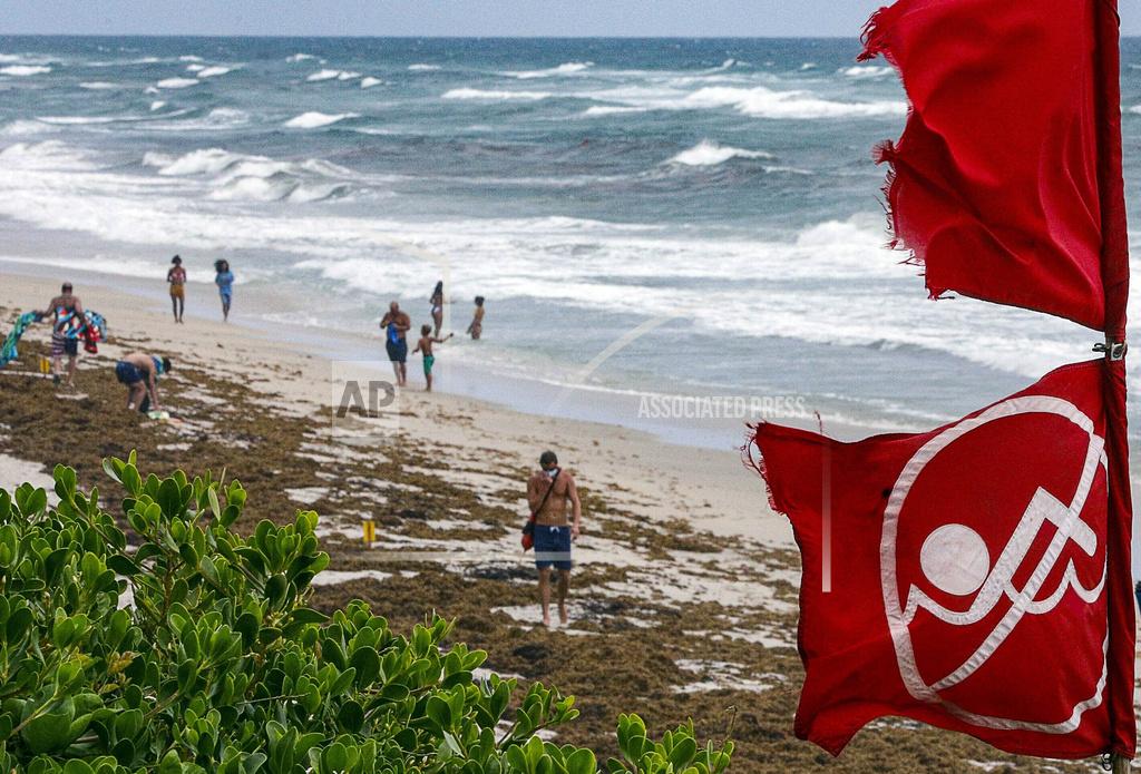 Damon Higgins Red no swimming flags fly at Lantana, Fla., Municipal Beach, Fla., as Hurricane Isaias approaches the Florida coast Saturday, Aug. 1, 2020. Isaias snapped trees and knocked out power as it blew through the Bahamas on Saturday and churned toward the Florida coast, where it is threatening to complicate efforts to contain the coronavirus in a hot spot.(Damon Higgins/The Palm Beach Post via AP)