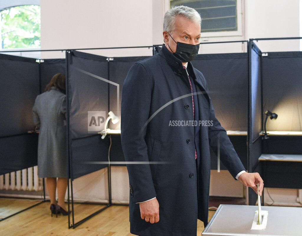 Uncredited Lithuania's President Gitanas Nauseda, wearing face masks to protect against coronavirus, casts his ballot at a polling station during the parliamentary elections in Vilnius, Lithuania, Sunday, Oct. 11, 2020. Polls opened Sunday for the first round of national election in Lithuania, where voters will renew the 141-seat parliament and the ruling four-party coalition is widely expected to face a stiff challenge from the opposition to remain in office. (Lithuanian President Office via AP)