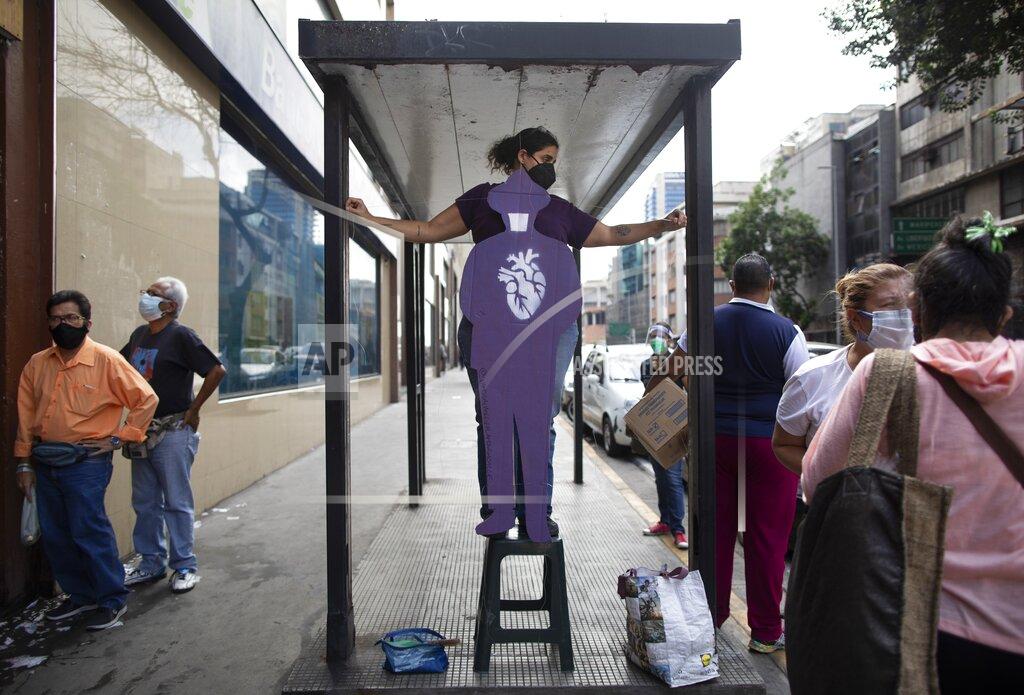 Ariana Cubillos Artist Susan Applewhite attaches her recycled cardboard cutout of the late Venezuelan Dr. Jose Gregorio Hernandez, popularly known as the "doctor of the poor, onto a bus stop bench, in downtown in Caracas, Venezuela, Saturday, April 24, 2021. Hernandez is set to be beatified by the Catholic church, a step towards sainthood, on April 30th in the Venezuelan capital. (AP Photo/Ariana Cubillos)