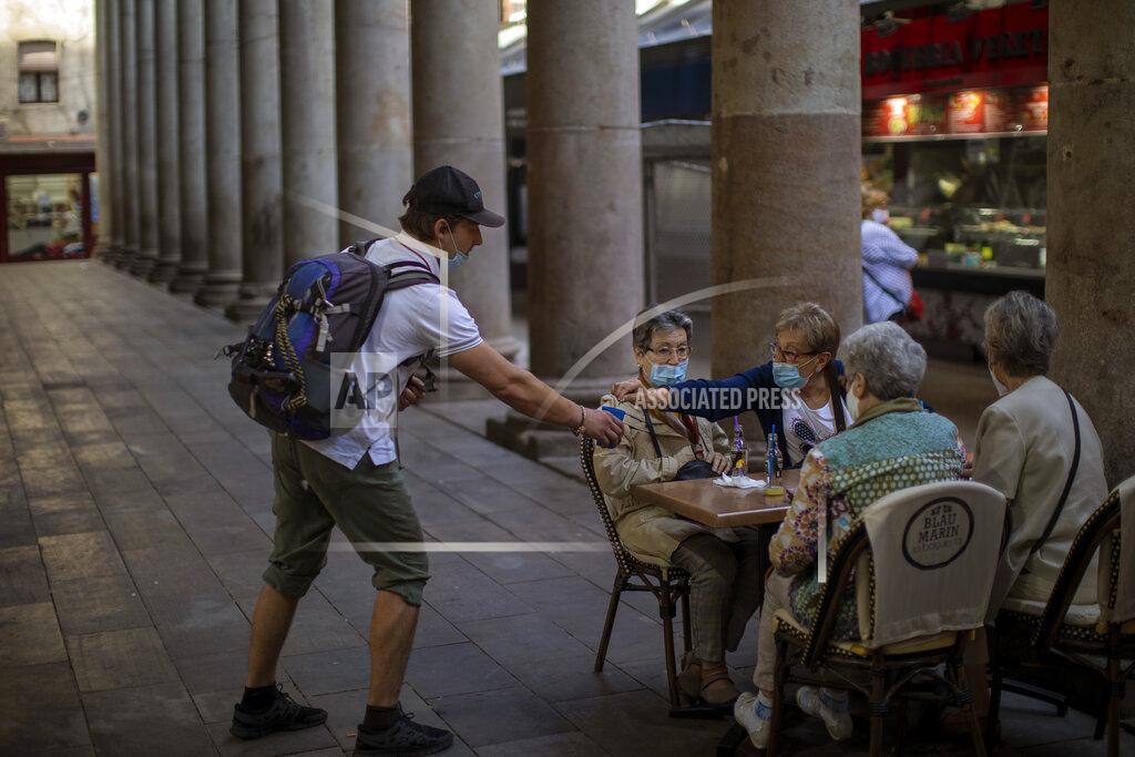 A woman gives alms to a beggar as they sit in a bar terrace during the coronavirus outbreak in Barcelona, Spain, Thursday, June 5, 2020. (AP Photo/Emilio Morenatti)