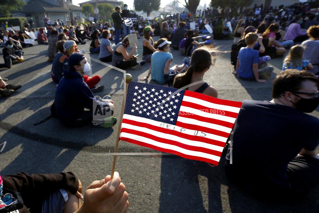 Rich Pedroncelli A protester holds up an American flag with the words "Help Us", Friday, June, 5, 2020 during demonstration in Sacramento, Calif, over the death of George Floyd. Floyd, a black man, died after being restrained by Minneapolis police officers on Memorial Day, May 25. (AP Photo/Rich Pedroncelli)
