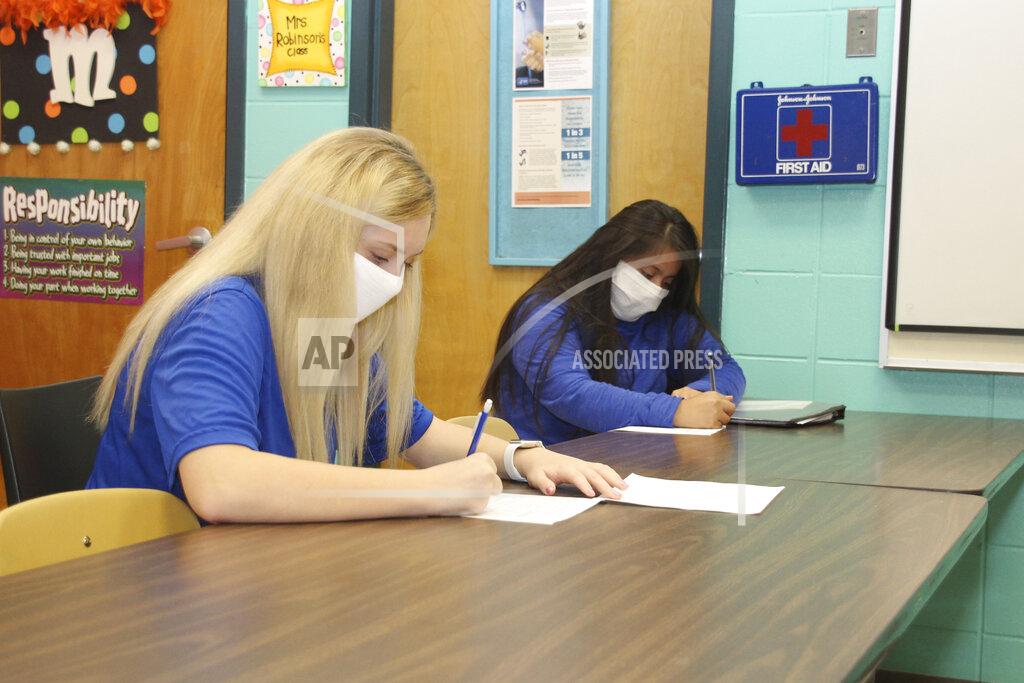 Janine Vincent Keeping a seat between them, sophomores' Natalie Brantley, 15, left and Yareny Aguilar-Perez, 15, are introduced to the principles of Early Childhood I at Newton County Career and Technical Center in Decatur, Miss., Monday, Aug. 3, 2020. Thousands of students across the nation are set to resume in-person school Monday for the first time since March. Parents are having to balance the children's need for socialization and instruction that school provides, with the reality that the U.S. death toll from the coronavirus has hit about 155,000 and cases are rising in numerous places. (Janine Vincent/Newton County Schools via AP)