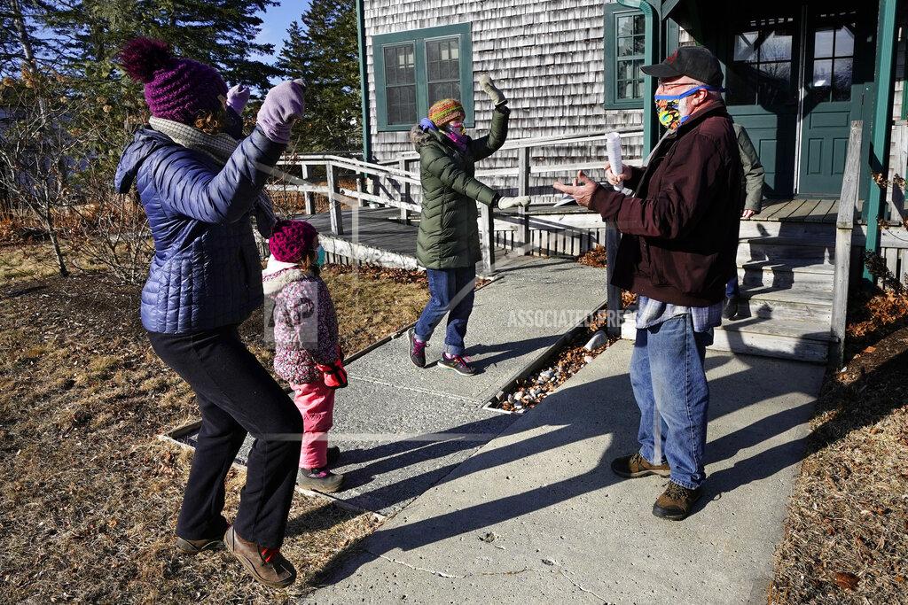 Robert F. Bukaty Island residents, Lindsay Eysnogle, left, her daughter, Marina Pickering and Kaitlyn Miller, center, do a happy dance with Mitchell McCormick to celebrate their COVID-19 vaccinations, Friday, March 19, 2021, on Islesford, Maine. Getting the vaccine to the world's farthest corners means delivering it by boat to Maine's islands, traveling by snowmobile to villages in Alaska and navigating complex waterways in Brazil's Amazon. (AP Photo/Robert F. Bukaty)