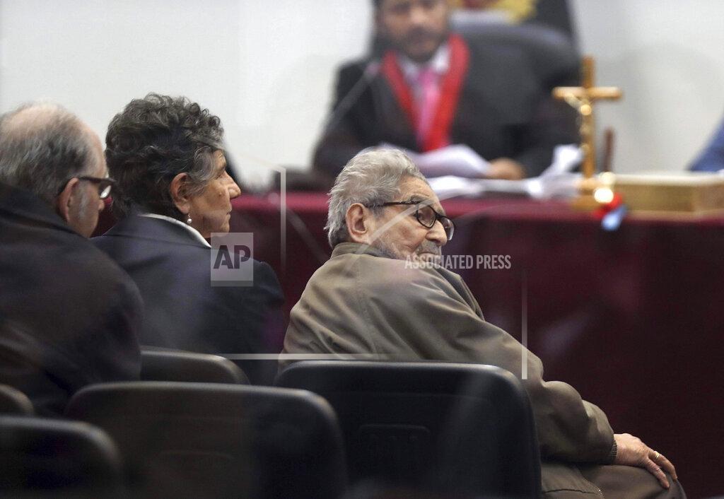 Martin Mejia FILE - In this Sept. 11, 2018 file photo taken through a window, Abimael Guzman, founder and leader of the Shining Path guerrilla movement, looks at his lawyer while siting with his partner Elena Iparraguirre, during the sentencing phase of their trial at a naval base in Callao, Peru. The Peruvian government reported Saturday, Sept. 11, 2021, that Guzman died after an illness. (AP Photo/Martin Mejia, File)