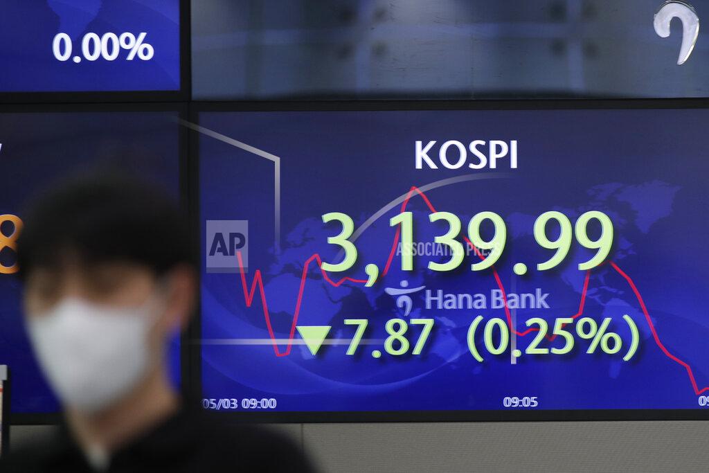 A currency trader walks by a screen showing the Korea Composite Stock Price Index (KOSPI) at a bank's foreign exchange dealing room in Seoul, South Korea, Monday, May 3, 2021. Shares were mostly lower in Asia in thin trading Monday, with many markets including those in Tokyo and Shanghai closed for holidays. (AP Photo/Lee Jin-man)