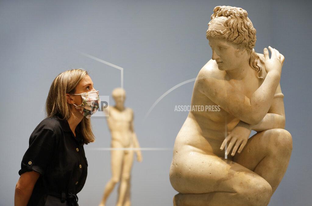Kirsty Wigglesworth A museum employee looks towards a marble statue of Crouching Venus, Roman, 2nd century AD, during a press view at The British Museum in London, Monday, Aug. 24, 2020. The museum will reopen to the public on Aug. 27. A new one-way route round the Ground Floor galleries will allow visitors access to many thousands of objects. (AP Photo/Kirsty Wigglesworth)