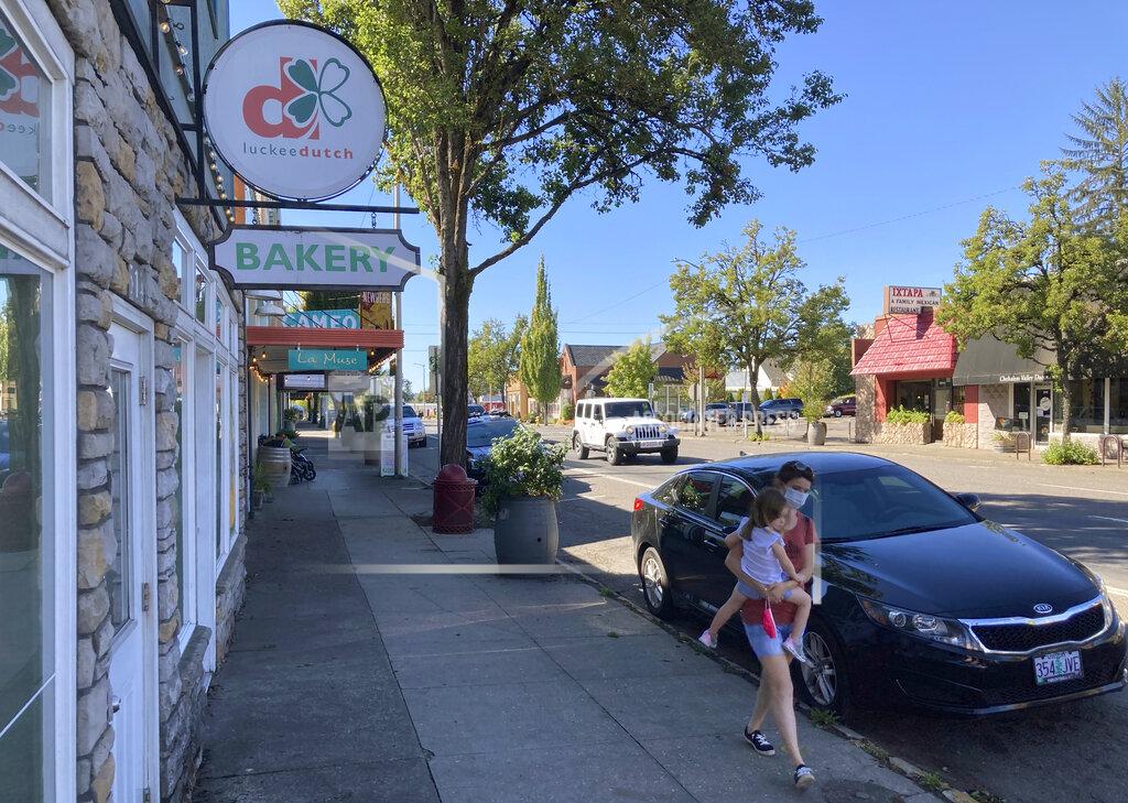 Andrew Selsky A woman and her child walk through downtown Newberg, Ore., on Tuesday, Sept. 21, 2021. The Chehalem Valley Chamber of Commerce told the school board that it has received numerous phone calls and emails from people saying they will boycott Newberg, the valley's main town, because of its ban on educators displaying Black Lives Matter and gay pride symbols in schools. (AP Photo/Andrew Selsky)