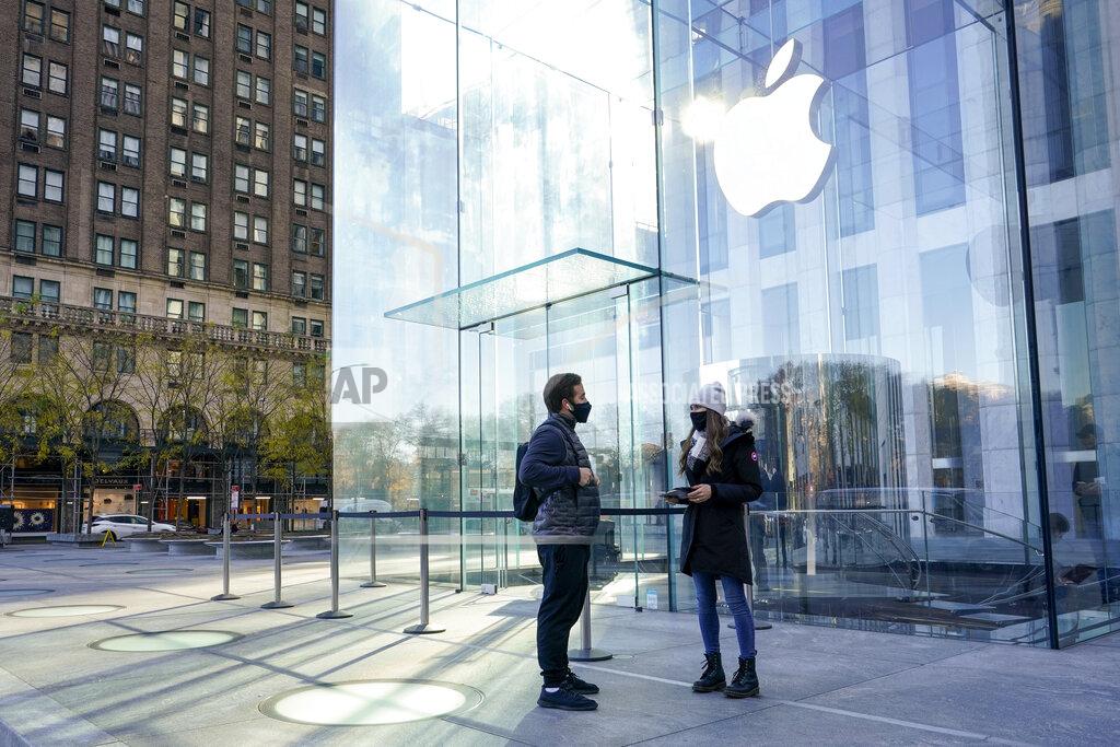 Mary Altaffer An Apple Store associate, right, wears a face mask as she helps a Black Friday shopper outside their store along Fifth Avenue, Friday, Nov. 27, 2020, in New York. (AP Photo/Mary Altaffer)