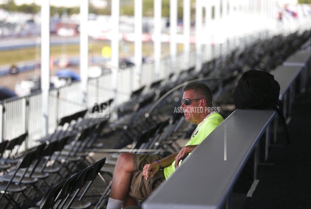 Jon Jenney, sits alone with no fans in the stand while working in the VIP area overlooking pit lane, at the IndyCar Grand Prix of St. Petersburg, Friday, March 13, 2020 in St. Petersburg. NASCAR and IndyCar have postponed their weekend schedules at Atlanta Motor Speedway and St. Petersburg, due to concerns over the COVID-19 pandemic. (Dirk Shadd/Tampa Bay Times via AP)