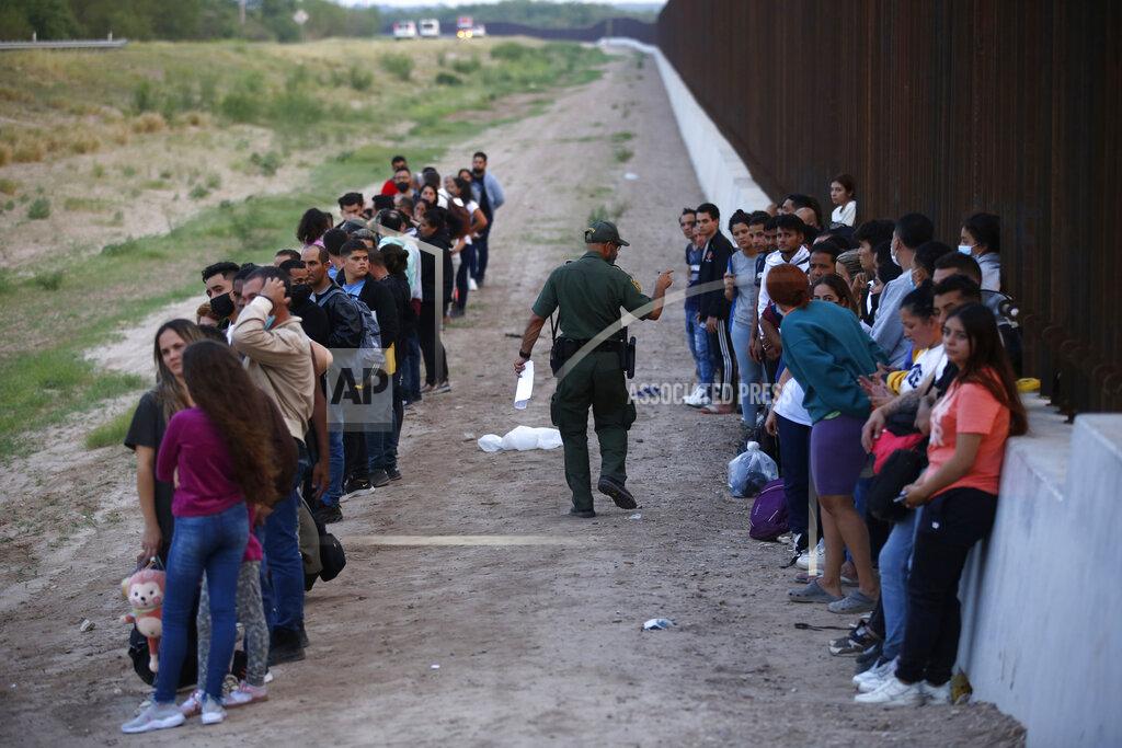 Dario Lopez-Mills A group of migrants stand next to the border wall as a Border Patrol agent takes a head count in Eagle Pass, Texas, Saturday, May 21, 2022. The Eagle Pass area has become increasingly a popular crossing corridor for migrants, especially those from outside Mexico and Central America, under Title 42 authority, which expels migrants without a chance to seek asylum on grounds of preventing the spread of COVID-19. (AP Photo/Dario Lopez-Mills)