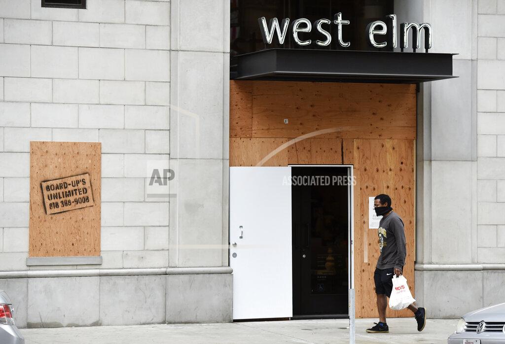 Chris Pizzello A pedestrian passes a boarded-up West Elm furniture store as stay-at-home orders continue in California due to the coronavirus, Friday, April 10, 2020, in Los Angeles. (AP Photo/Chris Pizzello)