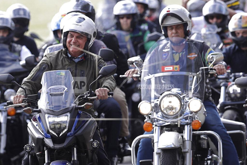 Eraldo Peres FILE - In this May 9, 2021 file photo, Brazil's President Jair Bolsoanro, left, takes a motorcycle tour with supporters representing the moto clubs in honor of Mother's Day, in Brasilia, Brazil. Bolsonaro has waged a 15-month campaign to downplay the virus’s seriousness and keep the economy humming, dismissing the pandemic early on as “a little flu” and has scorned masks. (AP Photo/Eraldo Peres, File)
