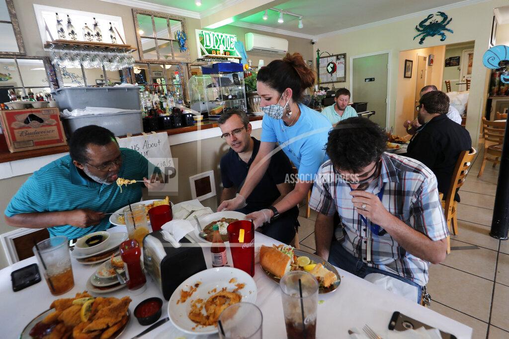 Gerald Herbert Waitress Gina Lauricella serves customers indoors, for the first time since the state shutdown, at Charles Seafood Restaurant in Harahan, La., Friday, May 15, 2020. Once a hot spot for coronavirus infections, Louisiana is officially easing up Friday on economically devastating business closures and public gathering restrictions that Gov. John Bel Edwards credits with slowing the spread of the virus. (AP Photo/Gerald Herbert)