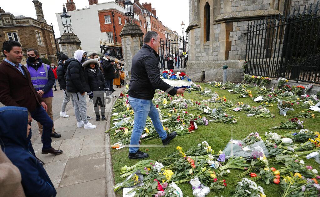 Frank Augstein A man prepares to lay a flower wreath outside the gates of Windsor Castle, a day after the death of Britain's Prince Philip, in Windsor, England, Saturday, April 10, 2021. Britain's Prince Philip, the irascible and tough-minded husband of Queen Elizabeth II who spent more than seven decades supporting his wife in a role that mostly defined his life, died on Friday. (AP Photo/Frank Augstein)