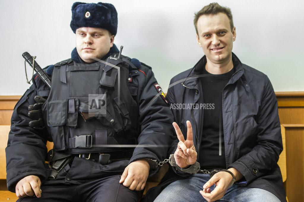 FILE - In this file photo taken on Thursday, March 30, 2017, Russian opposition leader Alexei Navalny, right, shows a V-sign for the media in court in Moscow, Russia. Russian opposition politician Alexei Navalny is in a coma and on a ventilator in an intensive care unit in Siberia after falling ill from suspected poisoning that his allies believe is linked to his political activity. (AP Photo/Evgeny Feldman, File)