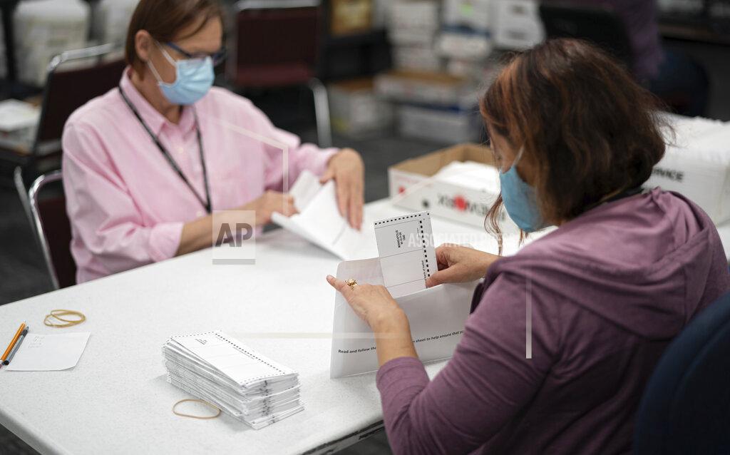 FILE - In this July 29, 2020, file photo, Lisa Finander, right, checks that each ballot has the voter's name on the ballot and mailing envelope and Laurie Mattila, left, checked that it was correct at Minneapolis Elections & Voter Services in Minneapolis. A three-judge panel of the 8th U.S. Circuit Court of Appeals said Thursday, Oct. 29, 2020 that Minnesota absentee ballots that arrive after Election Day should be separated from other ballots in case they are later invalidated by a court.(Glen Stubbe/Star Tribune via AP)