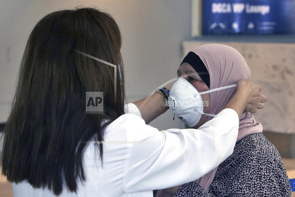 Bilal Hussein A healthcare worker adjusts the mask of a passenger who is departing the Rafik Hariri International Airport in Beirut, Lebanon, Wednesday, July 1, 2020. Beirut's airport is partially reopening after a three-month shutdown and Lebanon's cash-strapped government is hoping that thousands of Lebanese expatriates will return for the summer, injecting dollars into the country's sinking economy. (AP Photo/Bilal Hussein)