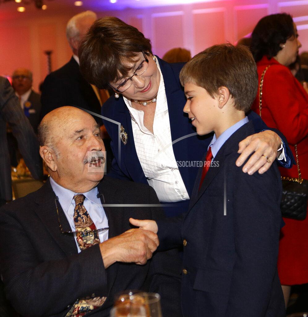 FILE - In this Dec. 12, 2012, file photo, former Louisiana Gov. Kathleen Blanco introduces her grandson Zachary Boulet to former Gov. Mike Foster, at a Council For a Better Louisiana panel discussion and luncheon in Baton Rouge, La. Foster, a folksy millionaire businessman who pushed major changes in education policy and lawsuit rules through an increasingly conservative state Legislature in the 1990s, died Sunday, Oct. 4, 2020. He was 90. Marsanne Goolsby, who was Foster’s press secretary when he was governor, said that Foster died at his home in Franklin. (AP Photo/Gerald Herbert, File)
