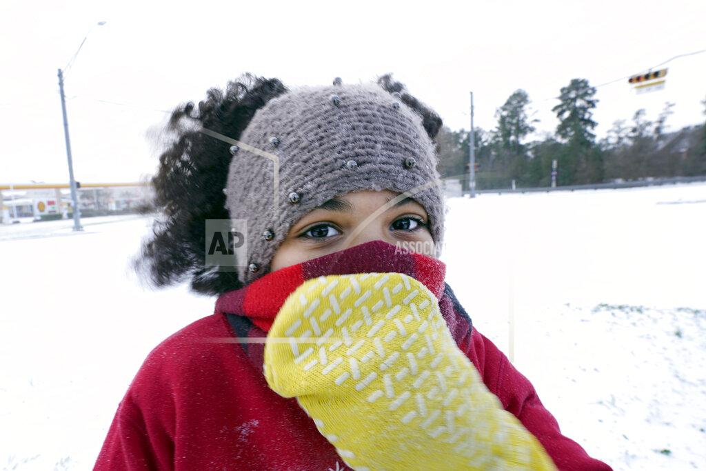 David J. Phillip Alyssa Remi, 12, tries to keep warm while playing in the snow Monday, Feb. 15, 2021, in Houston. A winter storm dropping snow and ice sent temperatures plunging across the southern Plains, prompting a power emergency in Texas a day after conditions canceled flights and impacted traffic across large swaths of the U.S. (AP Photo/David J. Phillip)