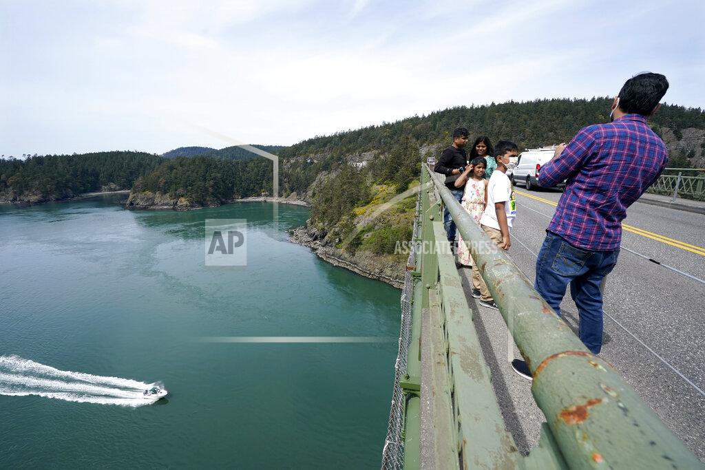 Elaine Thompson A family walks along the narrow sidewalk of the Deception Pass Bridge, a 976-foot span about 180-feet above the waters below, where work to replace corroded steel and paint the structure continues Thursday, April 29, 2021, in Deception Pass, Wash. Raising state taxes to improve roads and bridges is one of the few things many Republican and Democratic lawmakers have agreed on in recent years. Those efforts have slowed to a crawl this year, even as lawmakers acknowledge a widening gap between needed work and the money to pay for it. (AP Photo/Elaine Thompson)