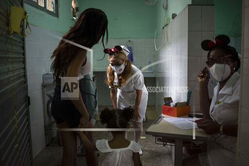 A nurse greets a young girl as she arrives with her mother to receive a dose of the Soberana-02 COVID-19 vaccine, in Havana, Cuba, Thursday, Sept. 16, 2021. Cuba began inoculating children as young as 2-years-old with locally developed vaccines on Thursday.(AP Photo/Ramon Espinosa)