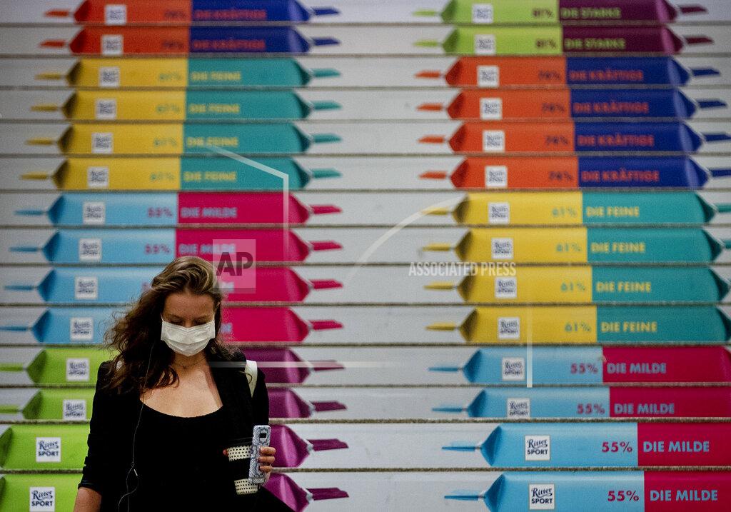 Michael Probst A woman with face mask walks down stairs with chocolate advertising in the main train station after arriving in Frankfurt, Germany, Wednesday, Sept. 16, 2020. (AP Photo/Michael Probst)