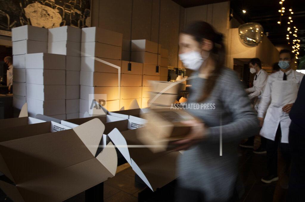 Virginia Mayo A staff member carries dinner boxes as she prepares part of nearly 600 take-away orders at Sergio Herman's Le Pristine restaurant in Antwerp, Belgium, Saturday, Nov. 7, 2020. Of all the many challenges the pandemic throws up for all kinds of professions, this one has been particularly tough: How to put a three-star chef into a takeout box. (AP Photo/Virginia Mayo)