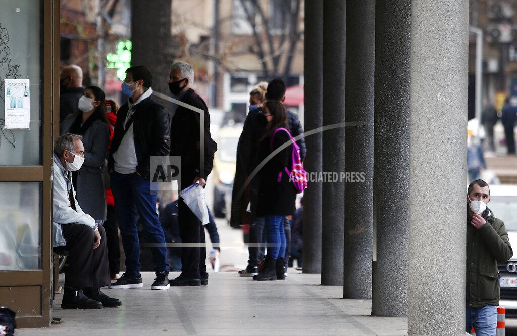 Boris Grdanoski In this picture taken on Tuesday, Dec. 29, 2020, people wait at the entrance of the University Clinic complex in Skopje, North Macedonia. When thousands of people across the European Union simultaneously began rolling up their sleeves last month to get a coronavirus vaccination shot, one corner of the continent was left behind, feeling isolated and abandoned: the Balkans. (AP Photo/Boris Grdanoski)